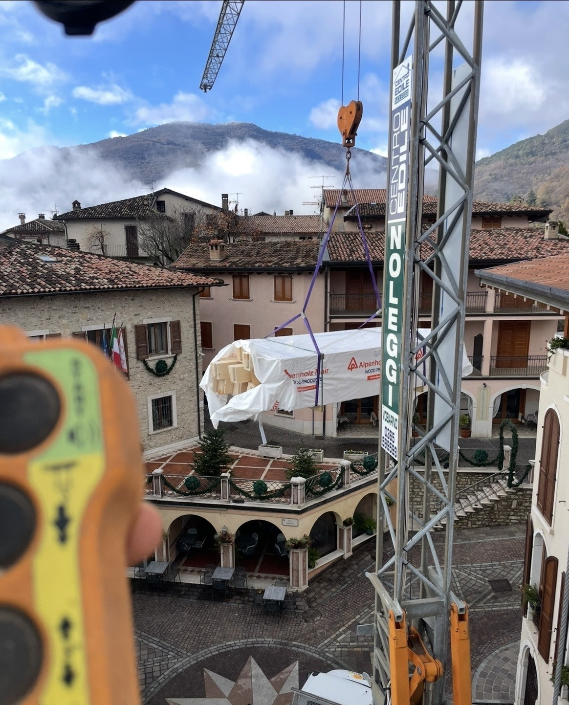 La gru porta in cantiere il legname nuovo per il tetto, imballato, sopra la piazza del paese