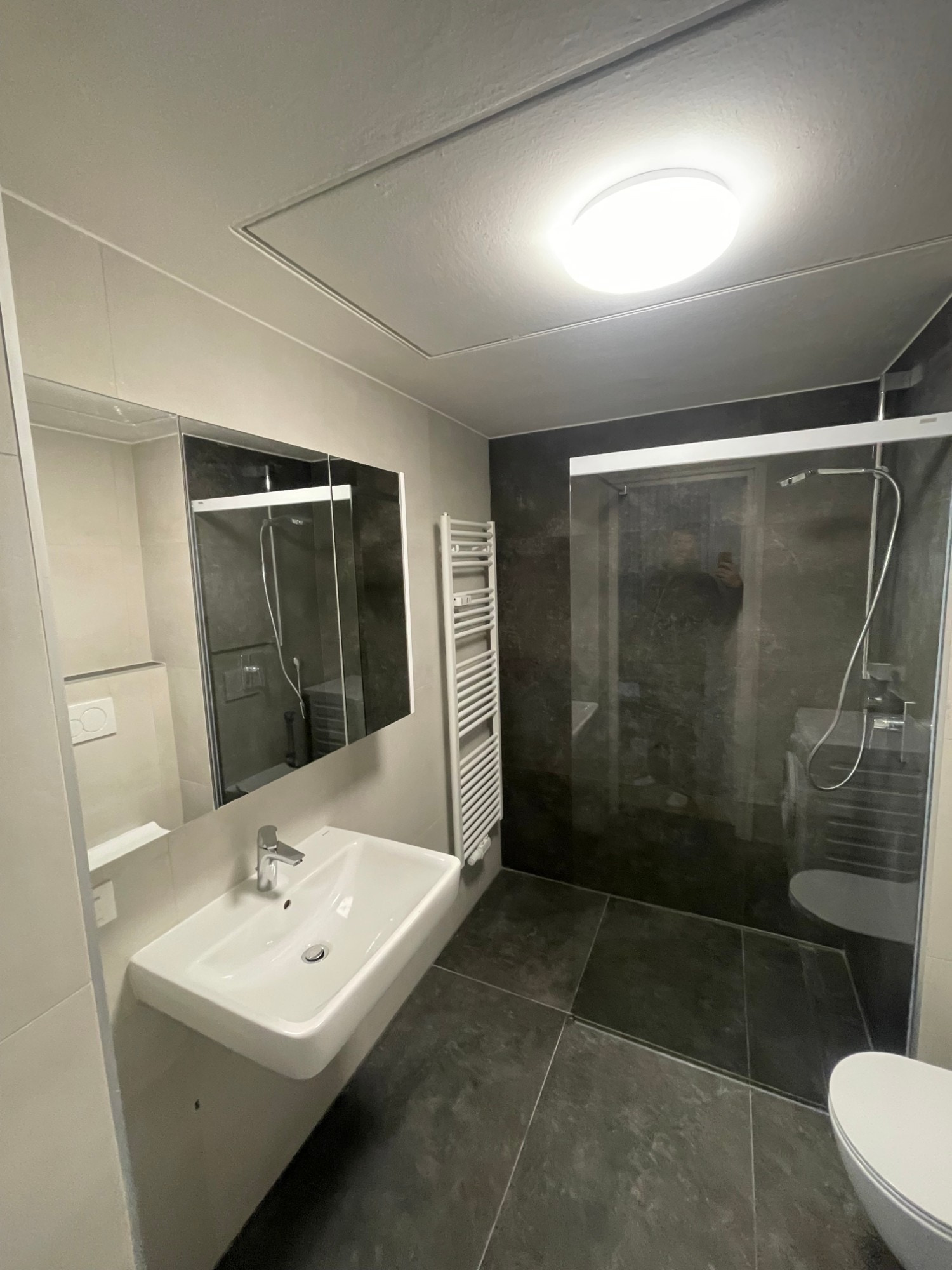 Bagno finito: lavabo sospeso, pensile a specchio, scaldasalviette e doccia a filo pavimento