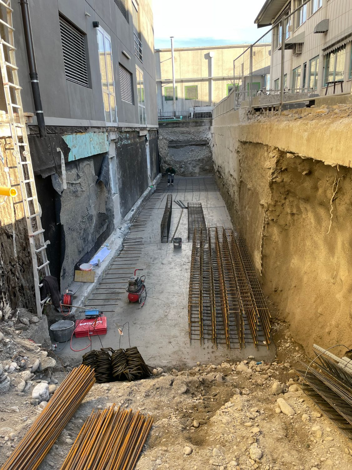 Scavo tra due edifici con il magrone gettato e le gabbie d’armatura pronte